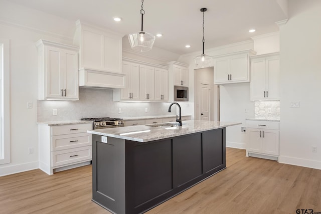 kitchen with stainless steel appliances, light wood-style flooring, a sink, and white cabinetry