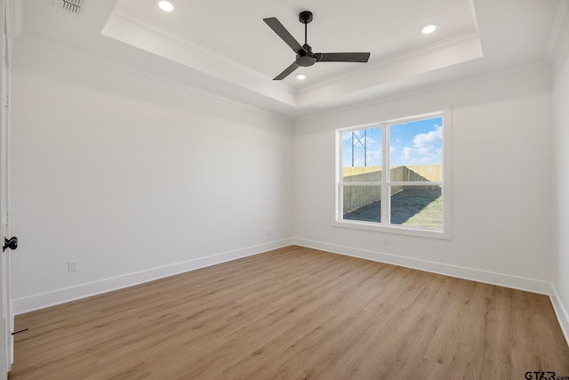 unfurnished room featuring light wood finished floors, baseboards, a tray ceiling, and ornamental molding