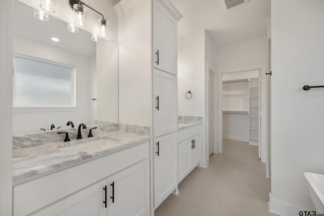 full bath featuring a bathing tub, vanity, visible vents, baseboards, and a spacious closet