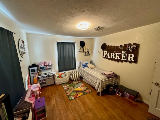 bedroom with hardwood / wood-style floors and a textured ceiling