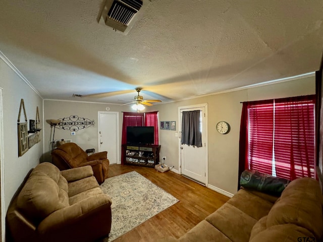 living room with ornamental molding, wood-type flooring, ceiling fan, and a textured ceiling