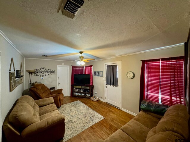 living room featuring a textured ceiling, ornamental molding, hardwood / wood-style flooring, and ceiling fan