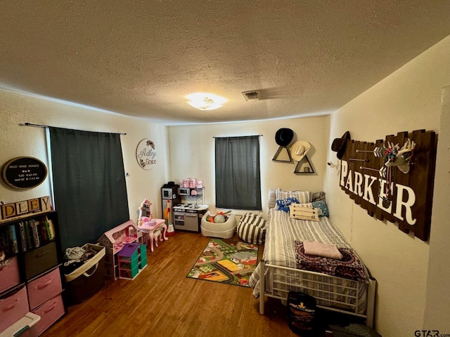 recreation room with a textured ceiling and hardwood / wood-style flooring