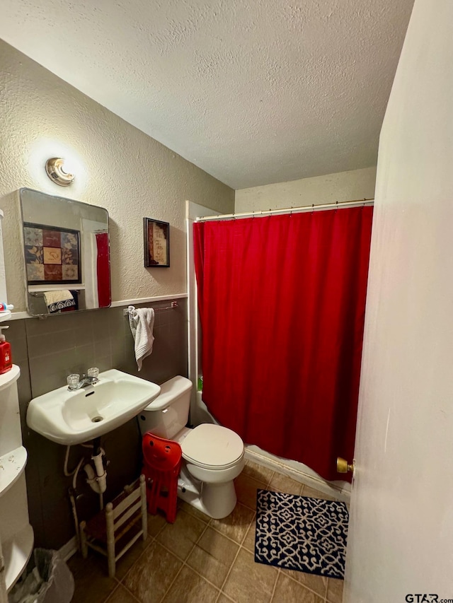 bathroom with toilet, sink, a textured ceiling, and tile patterned floors