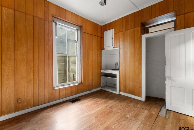 210 S Adams Ave, Tyler, TX 75702 - empty room with crown molding, light wood-style flooring, wooden walls, and visible vents
