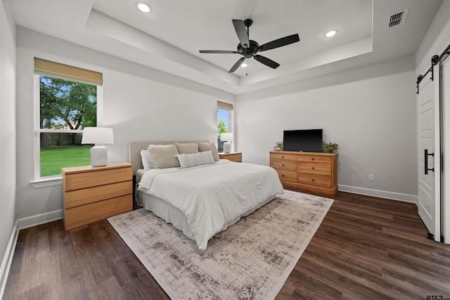 401 Deer Point Cv, Chandler, TX 75758 - bedroom featuring a barn door, a tray ceiling, multiple windows, recessed lighting, and dark wood finished floors
