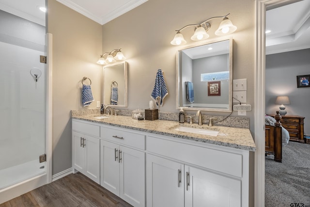 bathroom with vanity, crown molding, wood-type flooring, and a shower with door