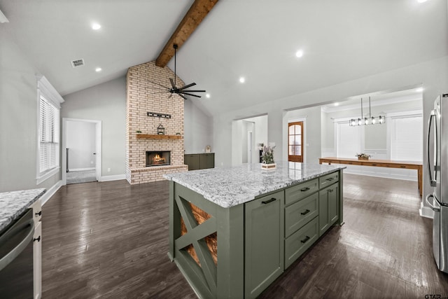 kitchen with green cabinets, a kitchen island, a fireplace, appliances with stainless steel finishes, and beam ceiling