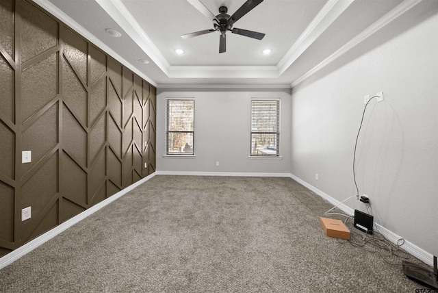 spare room featuring carpet flooring, ceiling fan, a raised ceiling, and ornamental molding