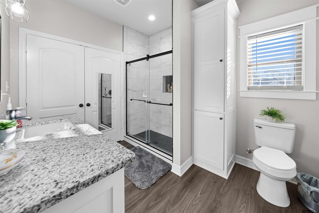 bathroom with hardwood / wood-style floors, vanity, toilet, and walk in shower