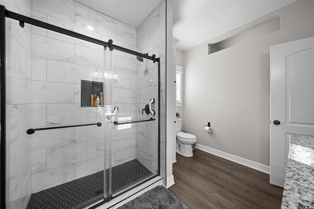 bathroom with hardwood / wood-style floors, toilet, and an enclosed shower