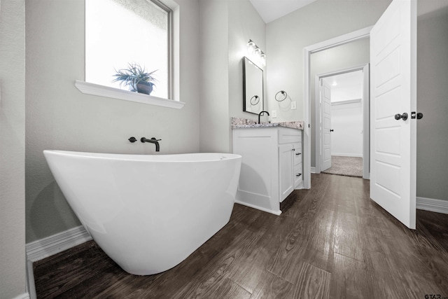 bathroom featuring hardwood / wood-style flooring, vanity, and a bath