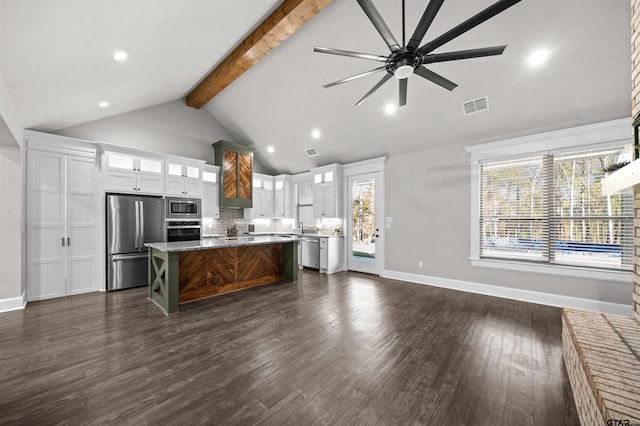 kitchen with a center island, dark wood-type flooring, stainless steel appliances, vaulted ceiling with beams, and white cabinets