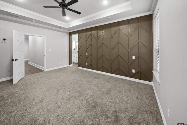 carpeted spare room featuring a raised ceiling, ceiling fan, and ornamental molding