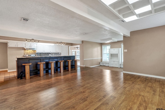 unfurnished living room with beamed ceiling, a textured ceiling, and dark hardwood / wood-style floors