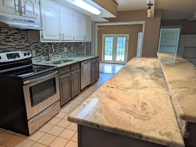 kitchen featuring white cabinetry, sink, stainless steel appliances, light stone counters, and backsplash