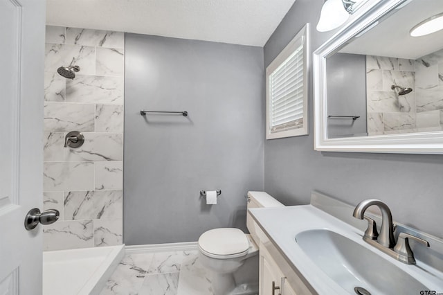 bathroom with vanity, toilet, and tiled shower