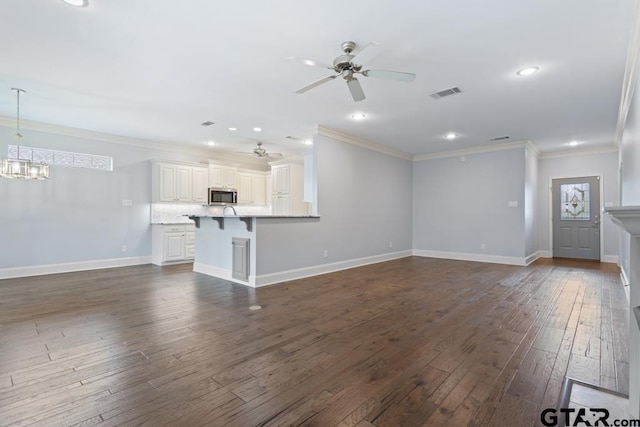 unfurnished living room featuring crown molding, visible vents, dark wood-type flooring, baseboards, and ceiling fan with notable chandelier