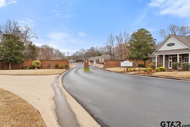 view of street featuring a gate, a gated entry, and curbs