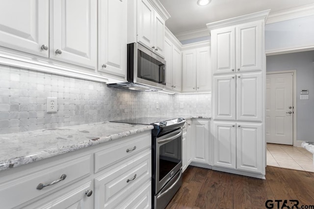 kitchen with stainless steel appliances, ornamental molding, white cabinetry, and tasteful backsplash