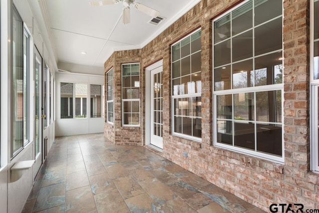 unfurnished sunroom featuring visible vents and a ceiling fan