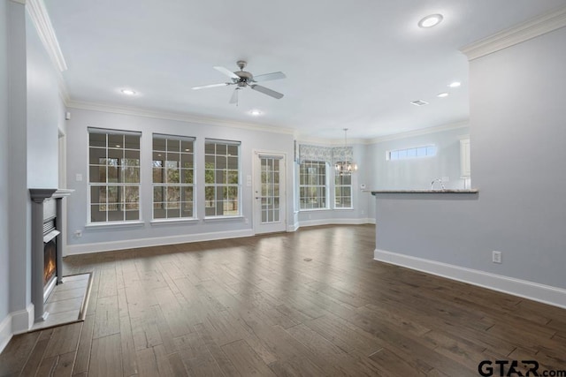 unfurnished living room featuring a lit fireplace, ornamental molding, dark wood-type flooring, and ceiling fan with notable chandelier