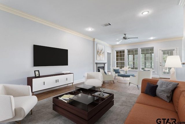 living area featuring ornamental molding, a fireplace, wood finished floors, and visible vents