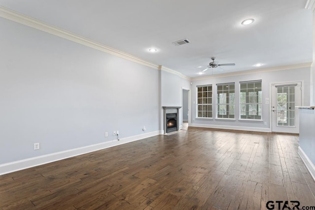 unfurnished living room featuring a warm lit fireplace, visible vents, dark wood finished floors, and ornamental molding