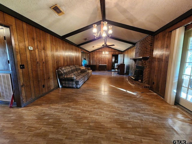 unfurnished living room featuring hardwood / wood-style floors, ceiling fan with notable chandelier, wood walls, and a textured ceiling