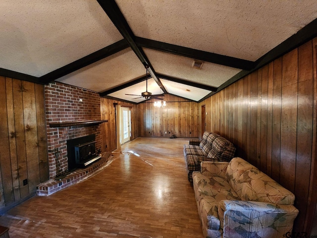 living room featuring lofted ceiling with beams, wooden walls, a textured ceiling, and light hardwood / wood-style flooring