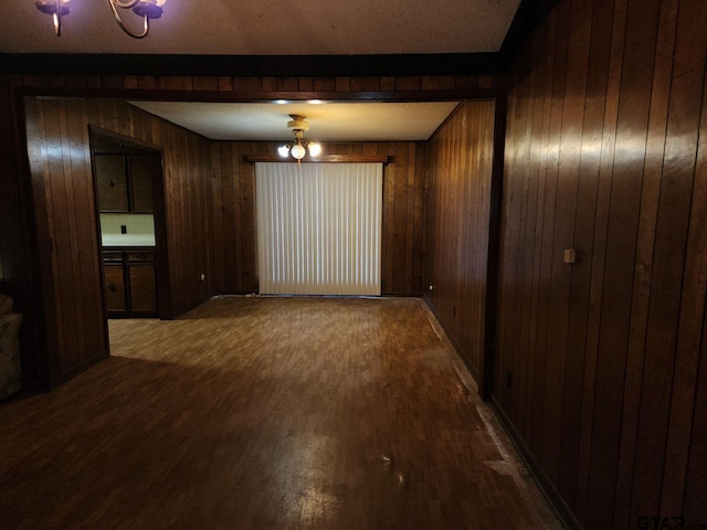 empty room featuring ceiling fan, wood-type flooring, wooden walls, and a textured ceiling