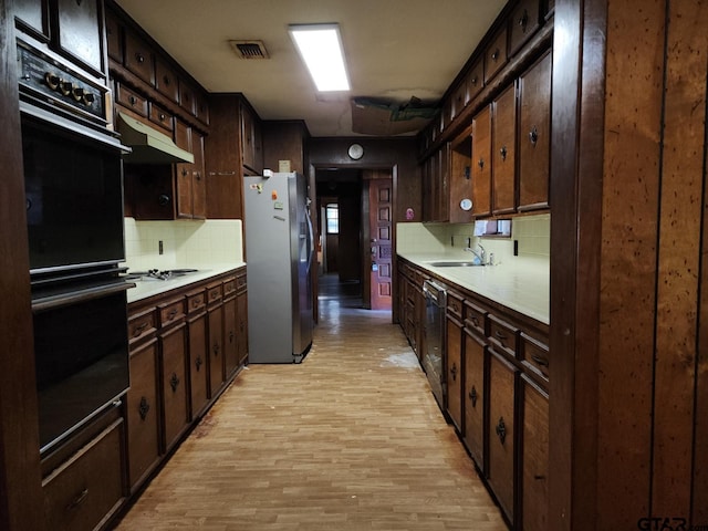 kitchen with black appliances, dark brown cabinets, and light hardwood / wood-style floors