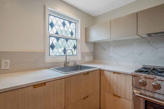 704 W 3rd St, Tyler, TX 75701 - kitchen featuring a sink, stainless steel gas range, tasteful backsplash, and light stone counters