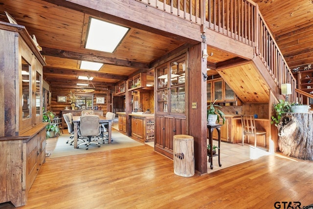 unfurnished dining area with light hardwood / wood-style floors, wooden ceiling, wood walls, and beamed ceiling