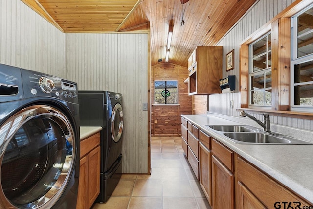 laundry room with washing machine and clothes dryer, wooden walls, wooden ceiling, cabinets, and sink