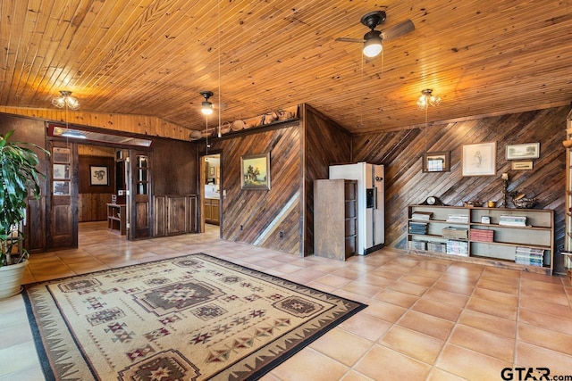 interior space featuring light tile patterned flooring, wood walls, and vaulted ceiling