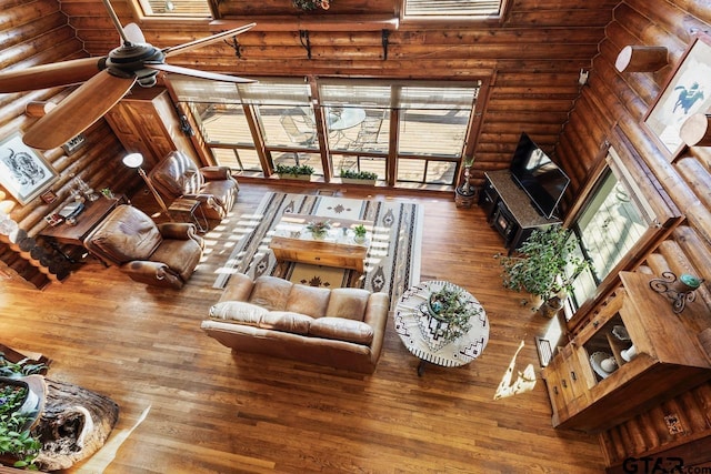 living room featuring hardwood / wood-style flooring, rustic walls, and a towering ceiling