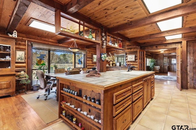 kitchen with beam ceiling, wooden ceiling, log walls, and tile countertops