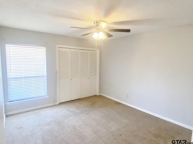 unfurnished bedroom featuring a closet, light carpet, ceiling fan, and baseboards