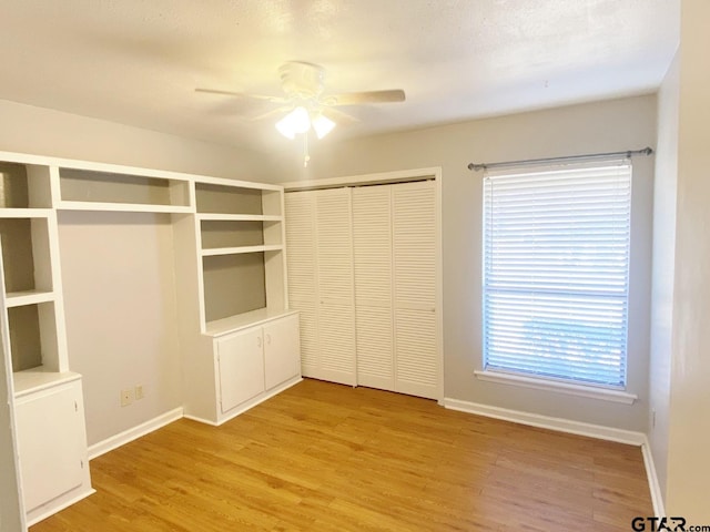 unfurnished bedroom featuring a closet, ceiling fan, light wood-style flooring, and baseboards