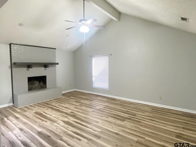 unfurnished living room with a brick fireplace, baseboards, beam ceiling, and wood finished floors