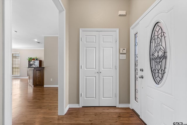 foyer entrance with ornamental molding and wood-type flooring