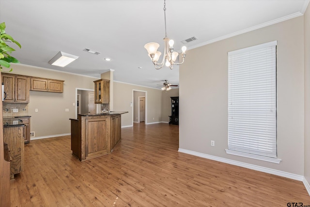 kitchen with hanging light fixtures, ceiling fan with notable chandelier, crown molding, and hardwood / wood-style floors