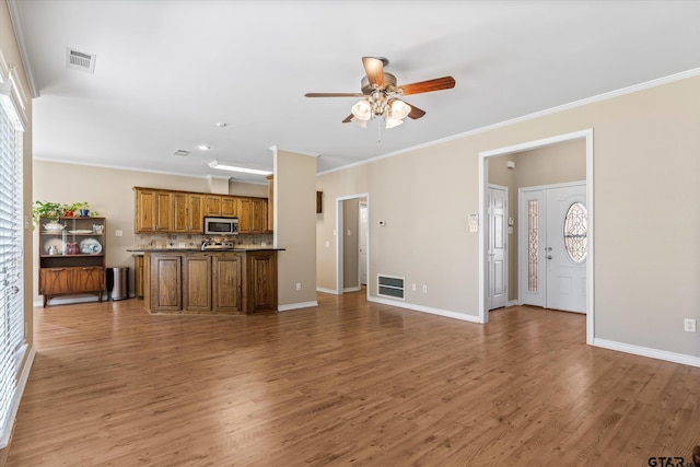 unfurnished living room with wood-type flooring, ceiling fan, and crown molding