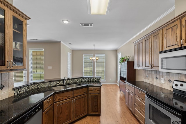 kitchen with stainless steel appliances, sink, light wood-type flooring, and backsplash