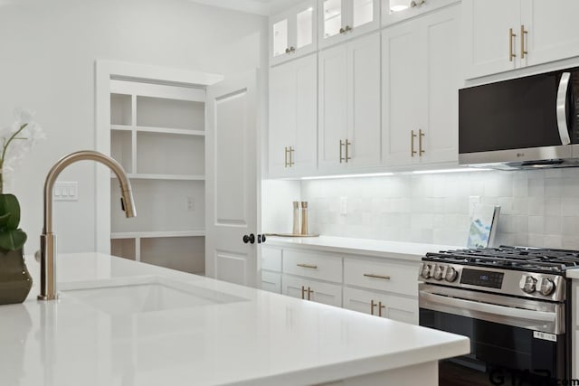 7201 Rolling Acres, Tyler, TX 75707 - kitchen with stainless steel appliances, backsplash, light countertops, and white cabinetry