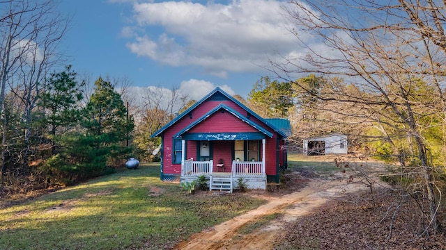 view of front facade with covered porch, a shed, and a front lawn