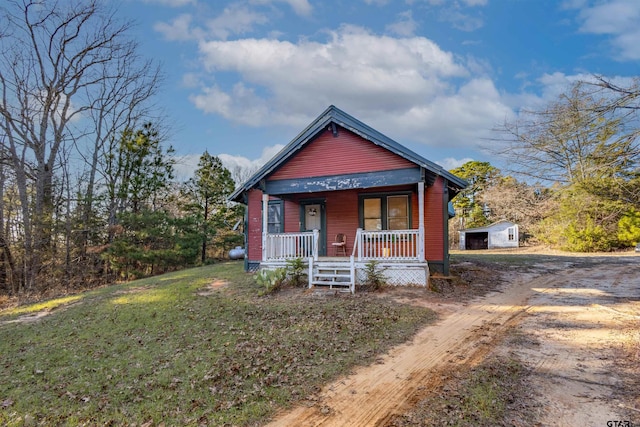 bungalow-style house featuring an outbuilding, a front yard, and covered porch