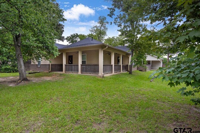 rear view of house featuring ceiling fan, a lawn, and a shingled roof