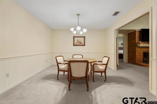 carpeted dining room with a chandelier and a fireplace